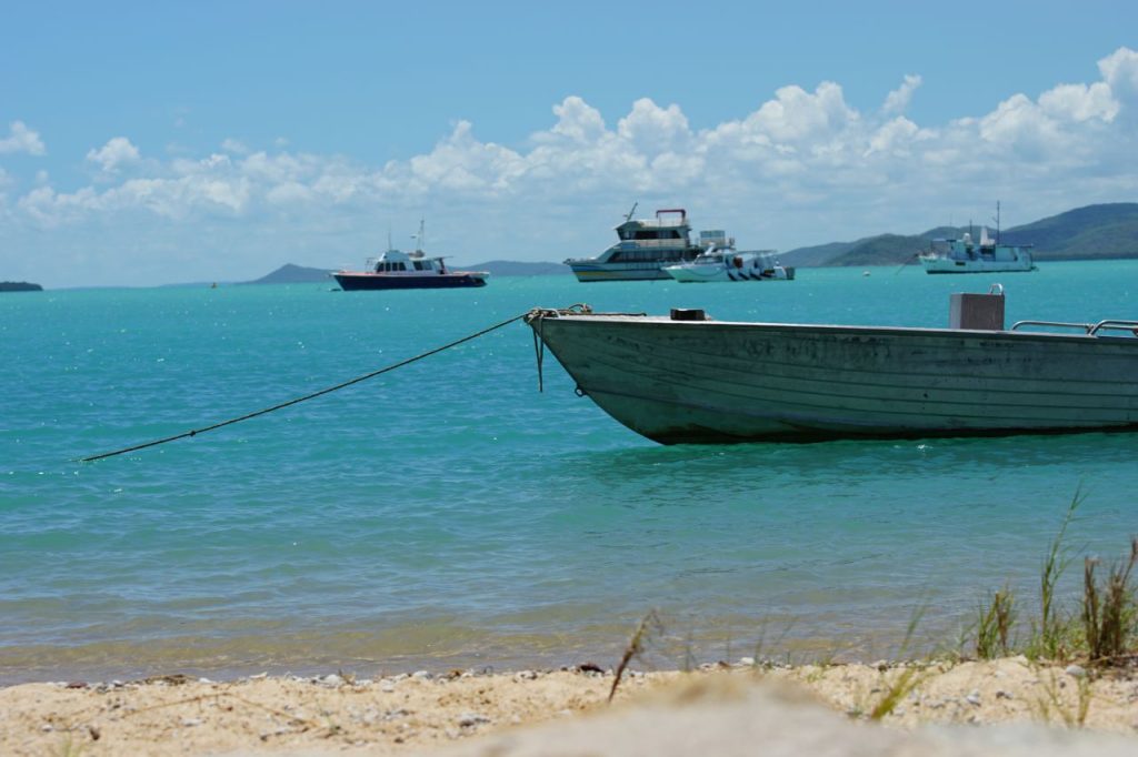 A boat moored at a beach with some other boats on the water in the distance