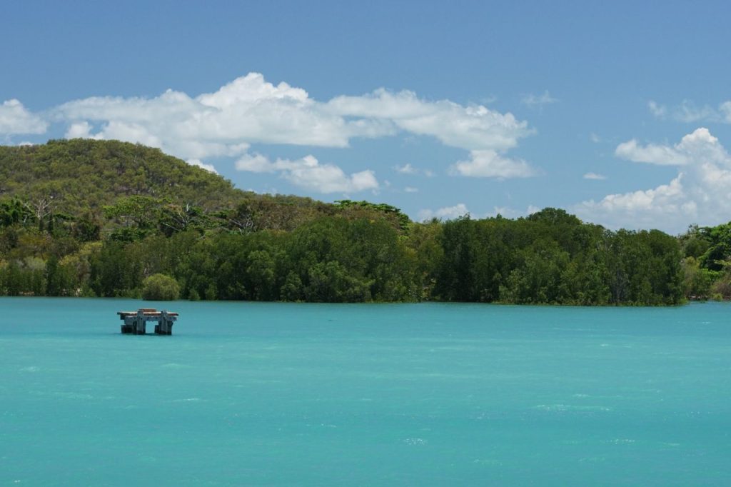 Beautiful blue water with trees in the distance and a blue sky with clouds